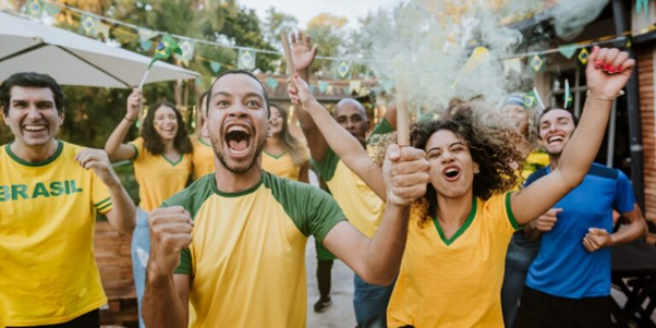 Feature image Pessoas comemorando a Copa do Mundo vestindo camisetas do Brasil em um ambiente festivo e animado.