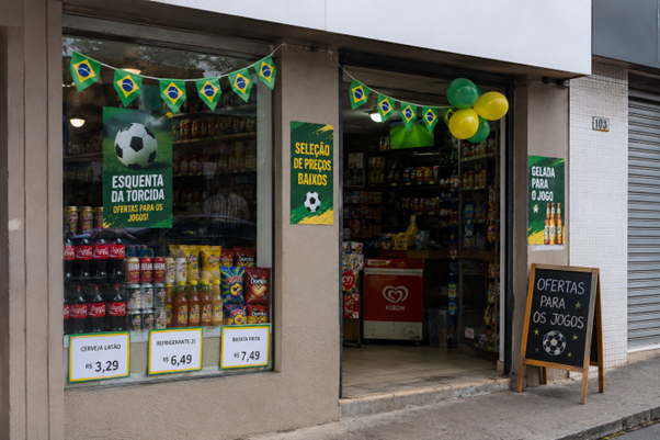 Vitrine de loja decorada para a Copa do Mundo com bandeirinhas do Brasil, ofertas promocionais e clima de torcida.