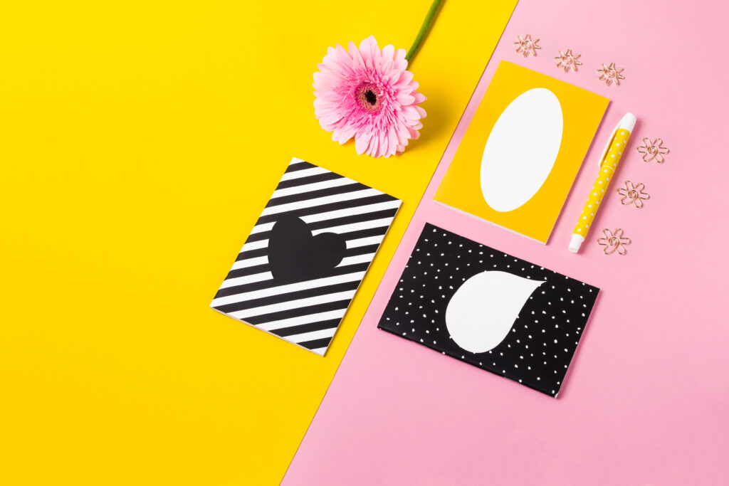 Cartões com design geométricos sobre fundo amarelo e rosa, representando tendências de papelaria personalizada em 2026.
