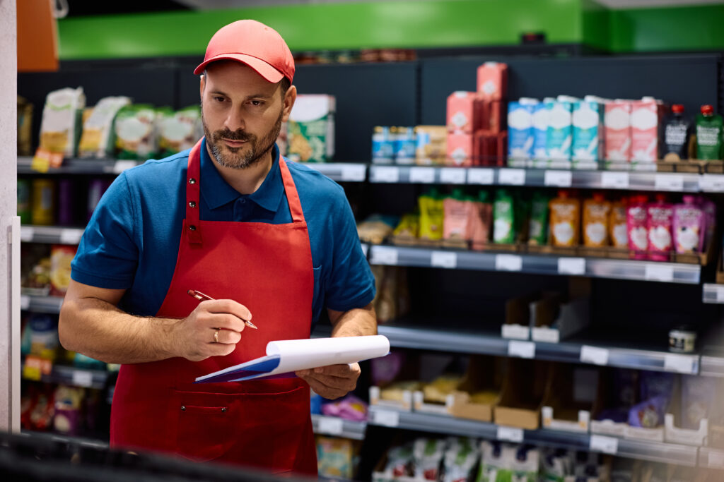 Varejista fazendo levantamento de estoque em loja para montar lista de produtos essenciais para seu negócio.
