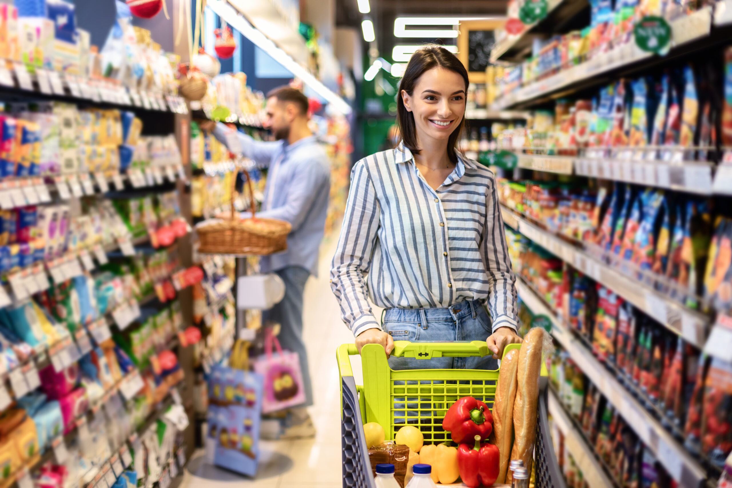 Cliente em supermercado de bairro com carrinho cheio de produtos frescos, ilustrando o crescimento do varejo de vizinhança em 2025.