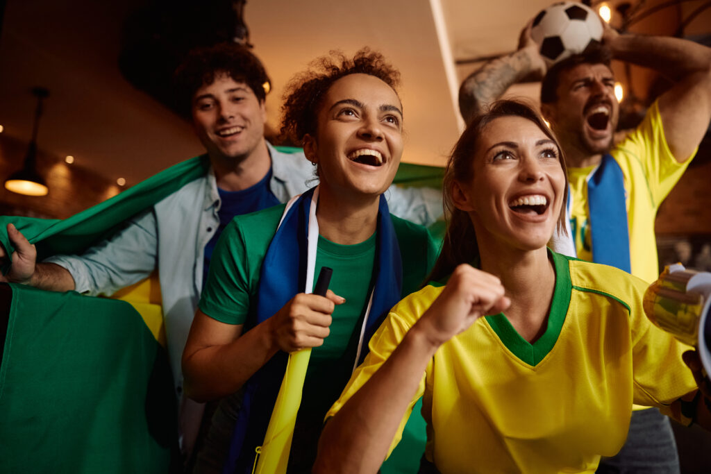 Torcedores exibindo bandeira do Brasil e roupas da torcida — oportunidades para vendas de camisas, kits e itens temáticos no varejo local.